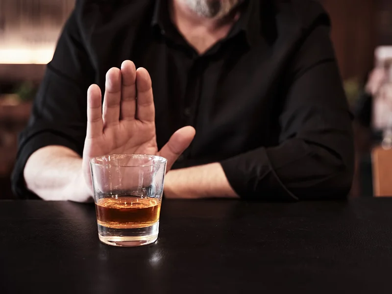 A man's hand rejecting an alcoholic drink.